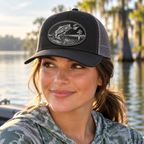 Female model wearing Flat River black and silver bass patch Richardson hat by a lake