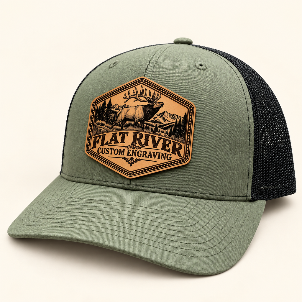 Flat River Bull Elk loden and black hat with engraved patch on ivory studio background