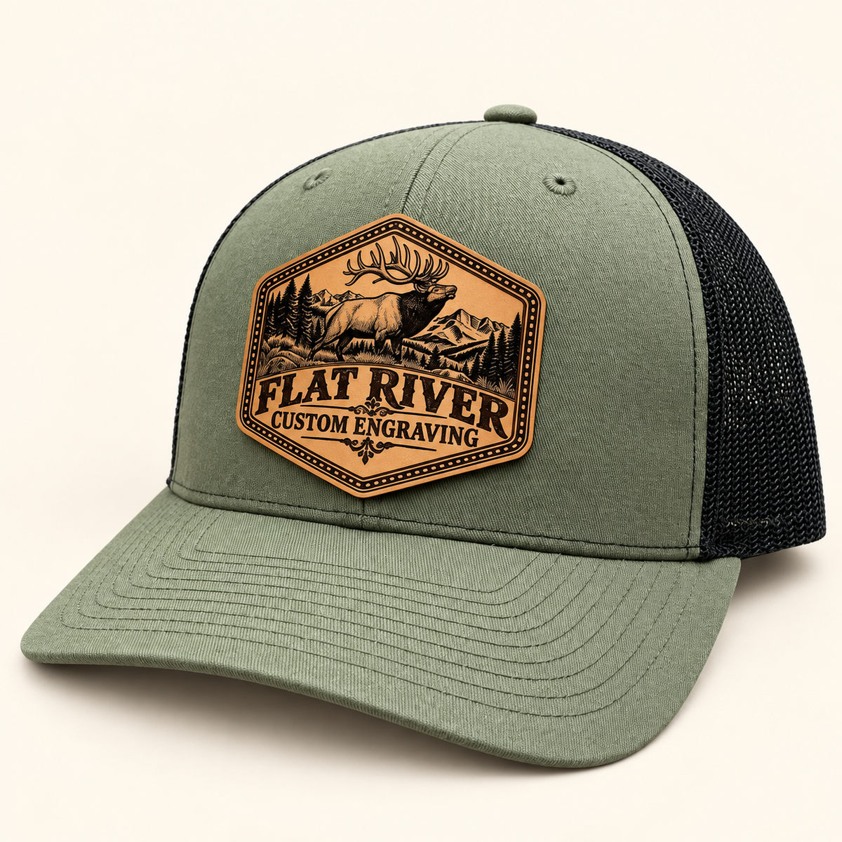 Flat River Bull Elk loden and black hat with engraved patch on ivory studio background
