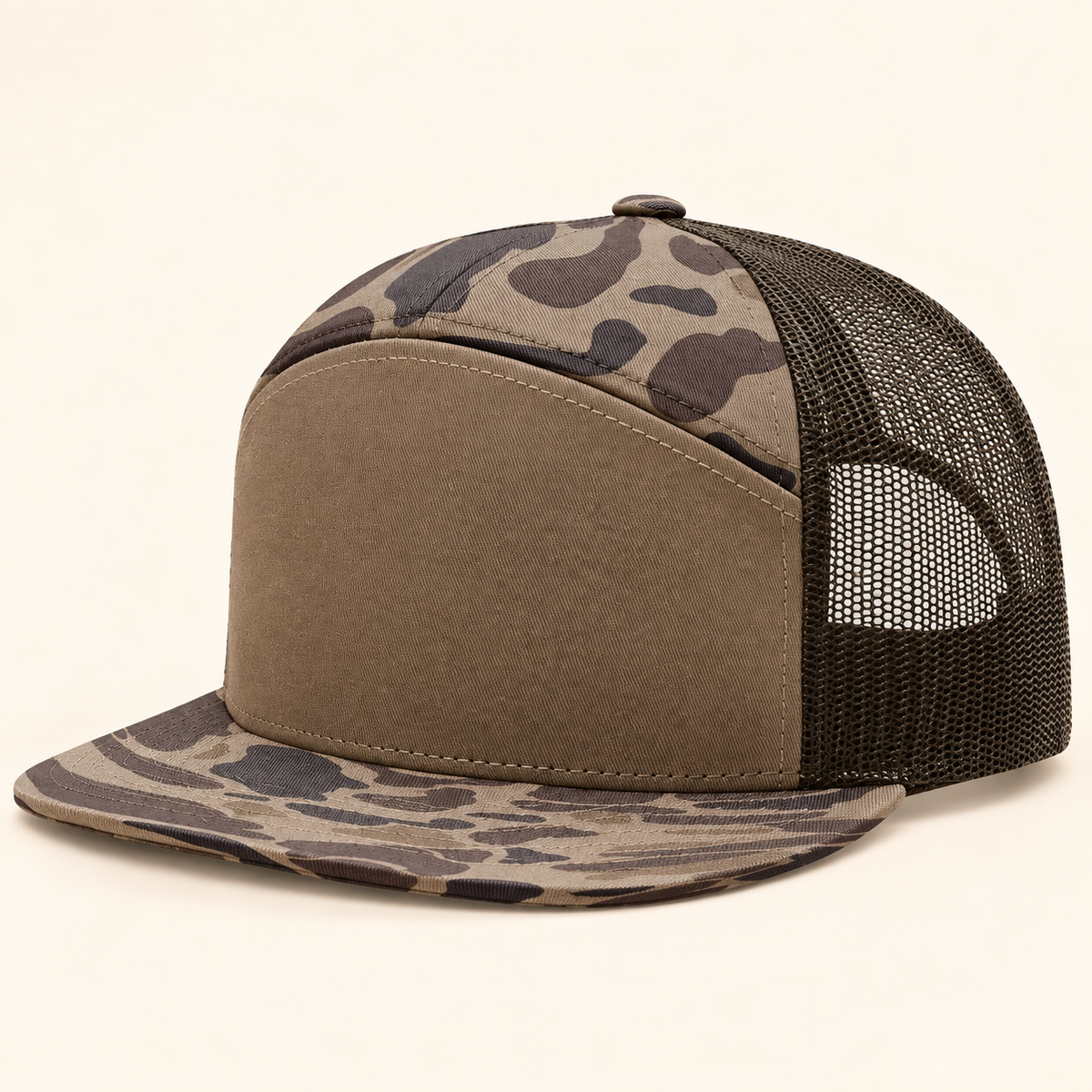 Studio image: Richardson 168P Bark Duck Camo/Brown blank seven-panel cap on warm cream background. Pictured color differs from the Black/Camo/Loden order option.