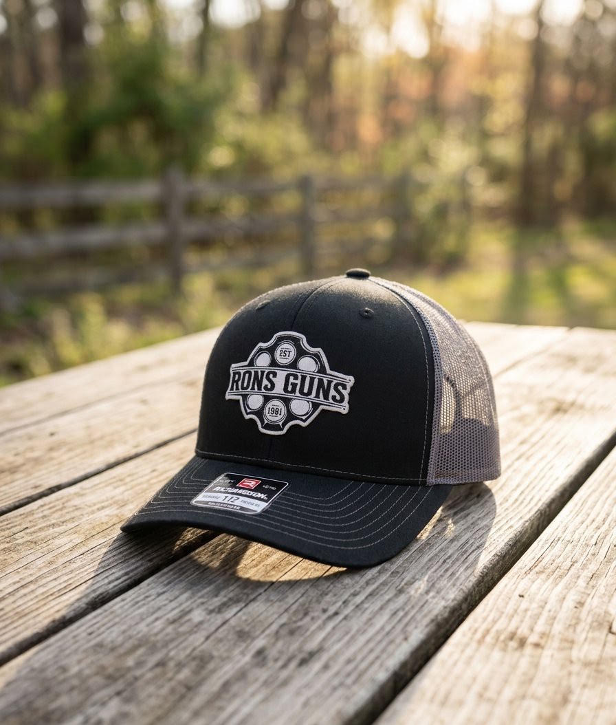 Ron’s Guns custom-logo patch hat on a wooden table — design mockup