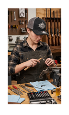 Woman wearing a Ron’s Guns custom patch hat in a gunstore workshop
